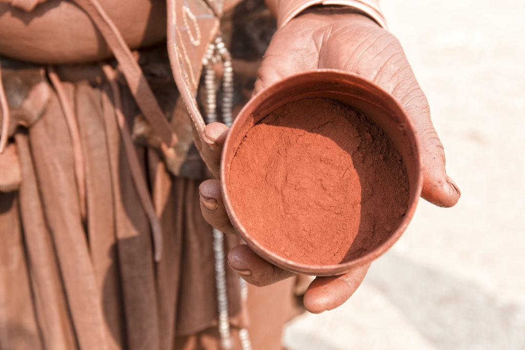 Himba villager holds container of red ochre