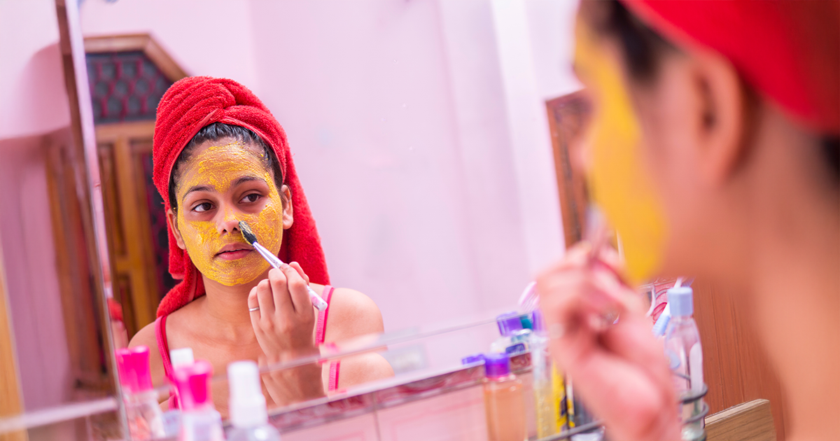 A woman in the front of mirror applying a besan face pack for glowing skin