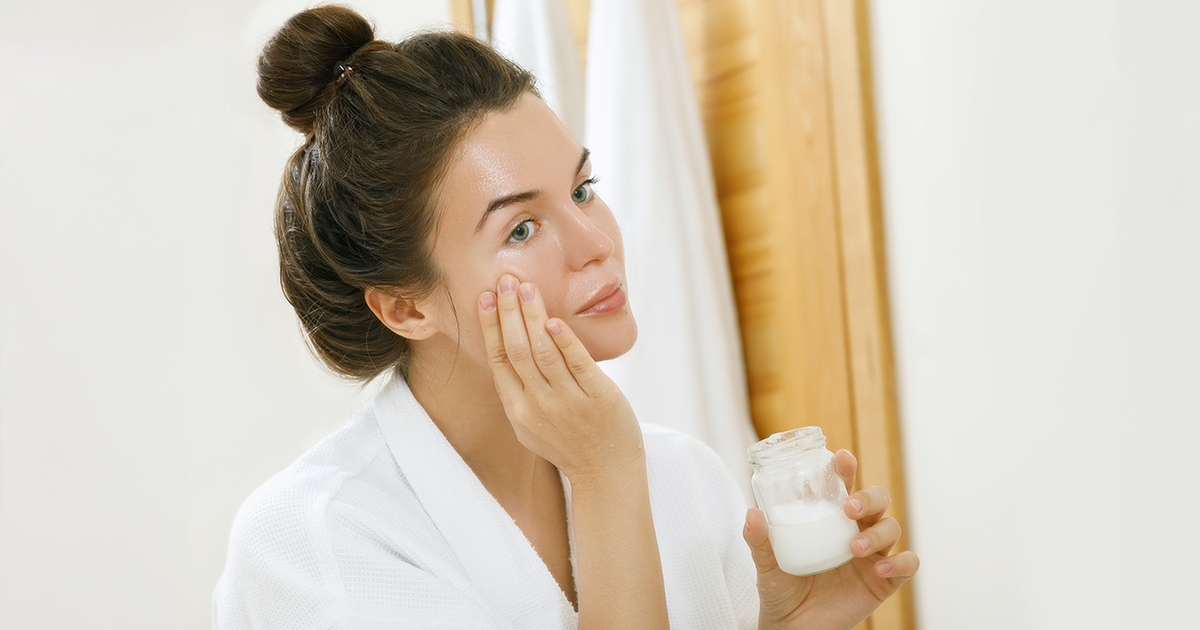 A woman applying a coconut oil on her face