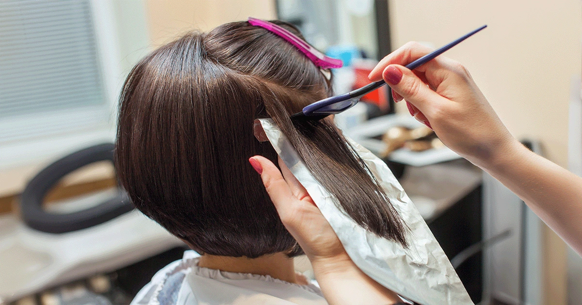 Image is showing a women doing chemical hair treatment at salon.