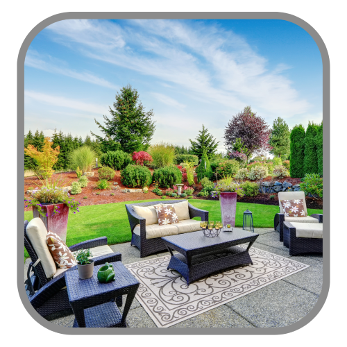 Backyard patio with furniture, green lawn and a berm with diverse plantings and trees