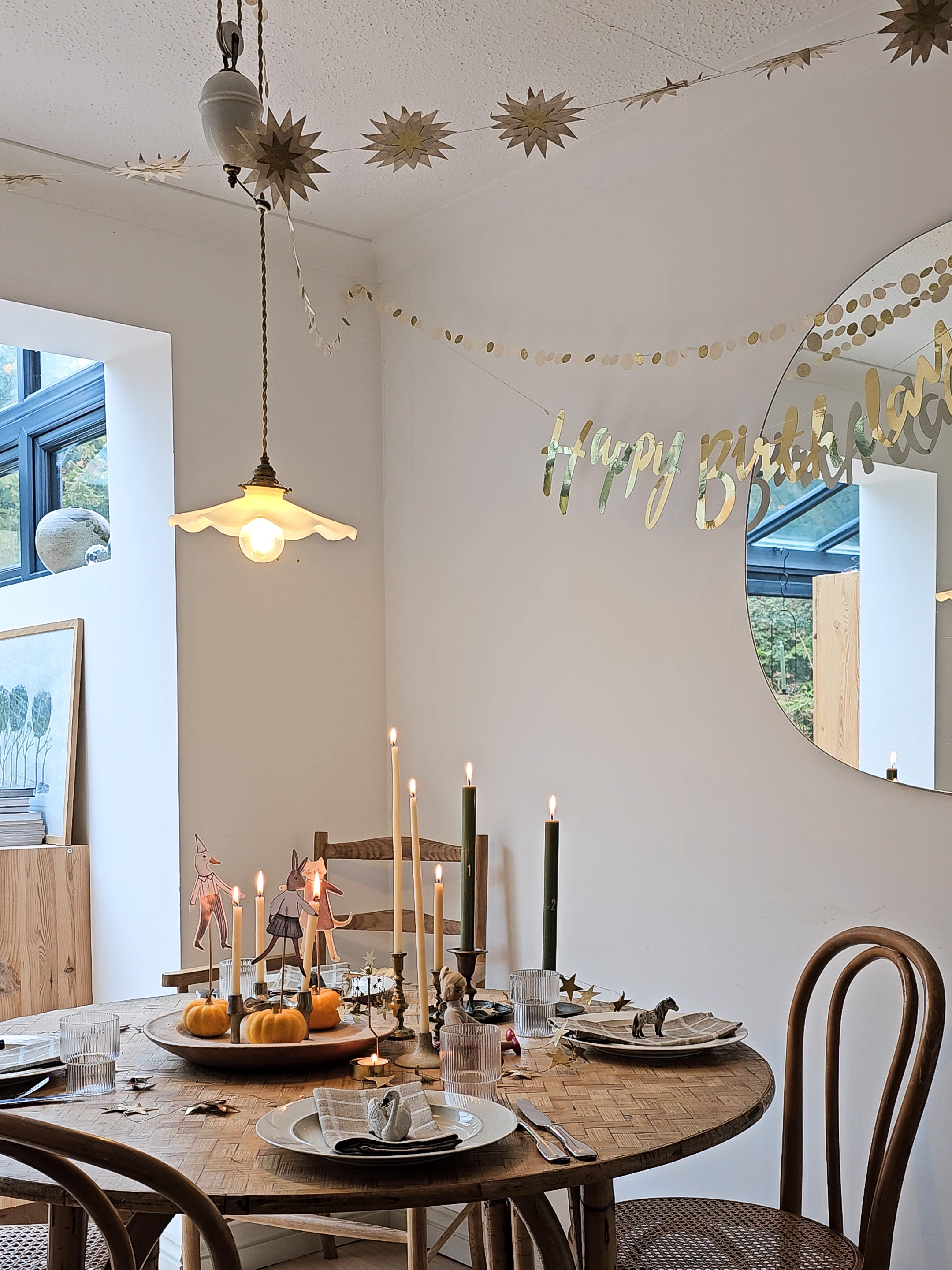 A candlelit celebratory table with garlands hanging around the room. 