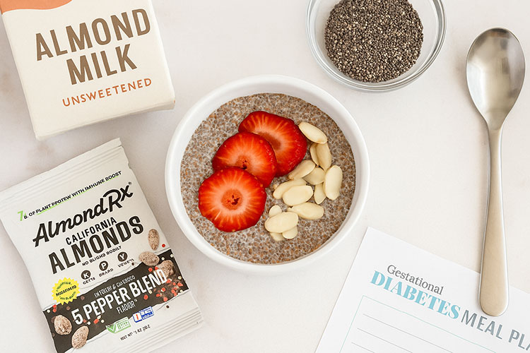 Top-down view of chia pudding topped with strawberries and blanched AlmondRx almonds, next to almond milk and a gestational diabetes meal plan.