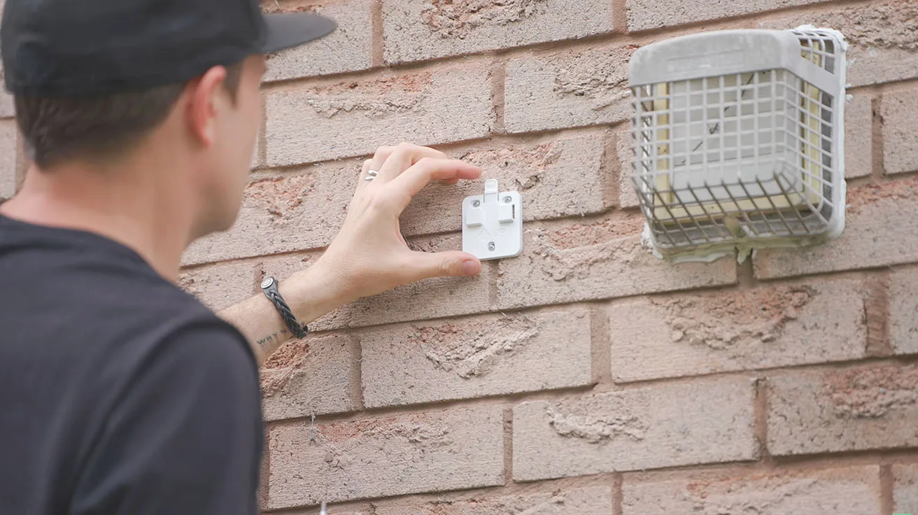 installer holding base plate against brick wall