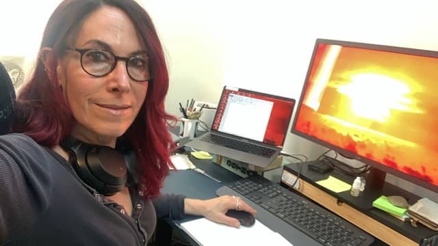 A woman sitting at a desk with a computer in front of her.