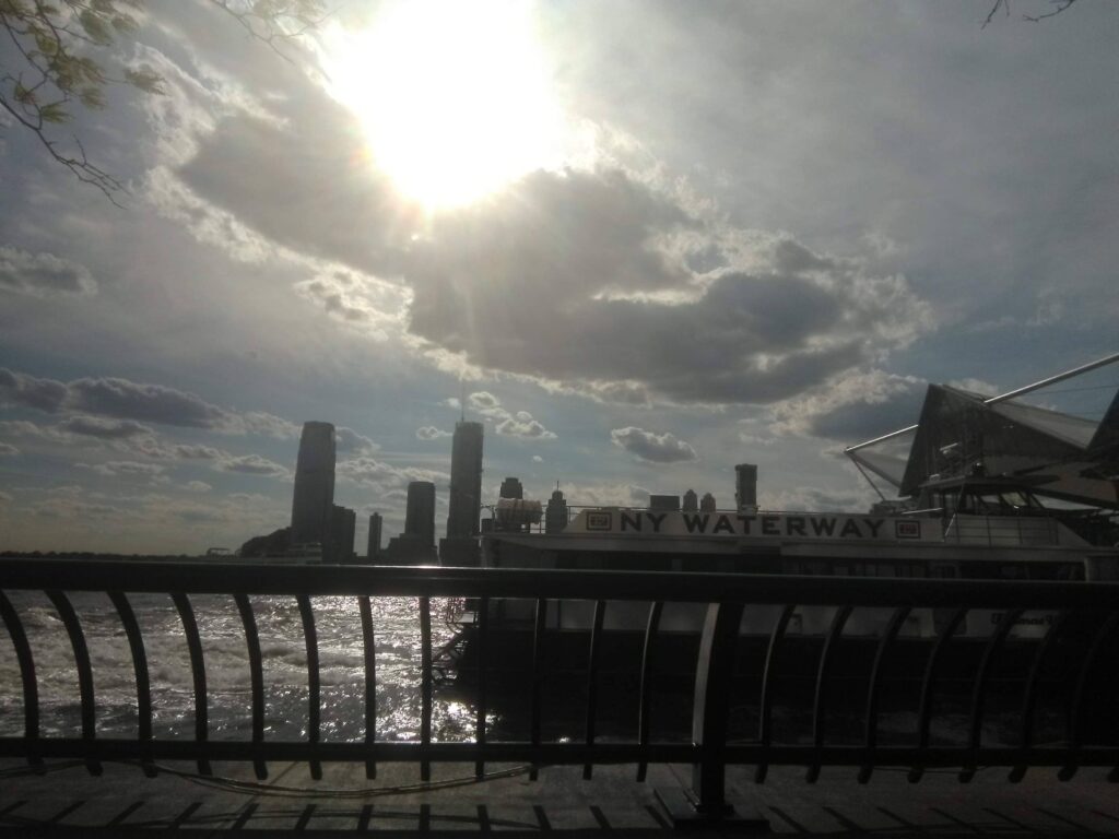 The sun is shining over a city with a bridge in the background.