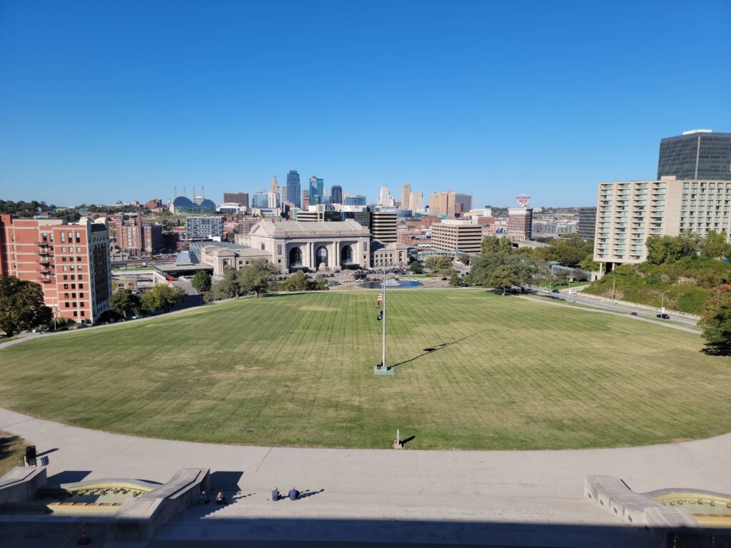 a large grassy field in front of a city.