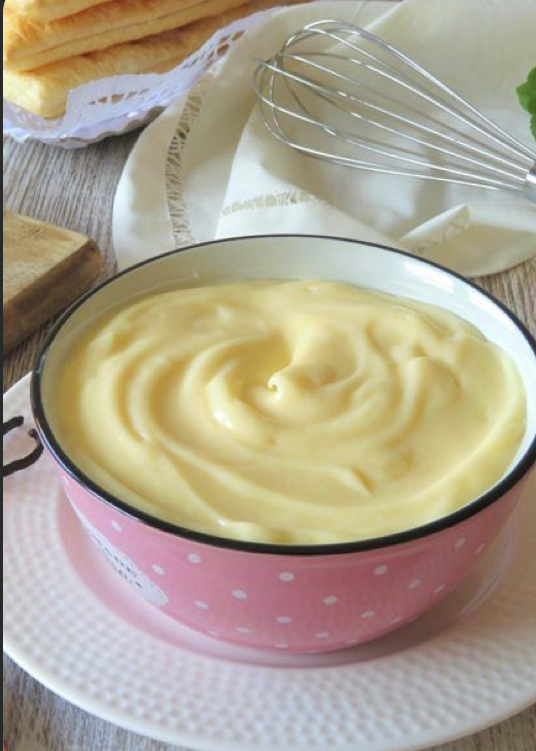 Crema pastelera en un tazón rosa con puntos blancos