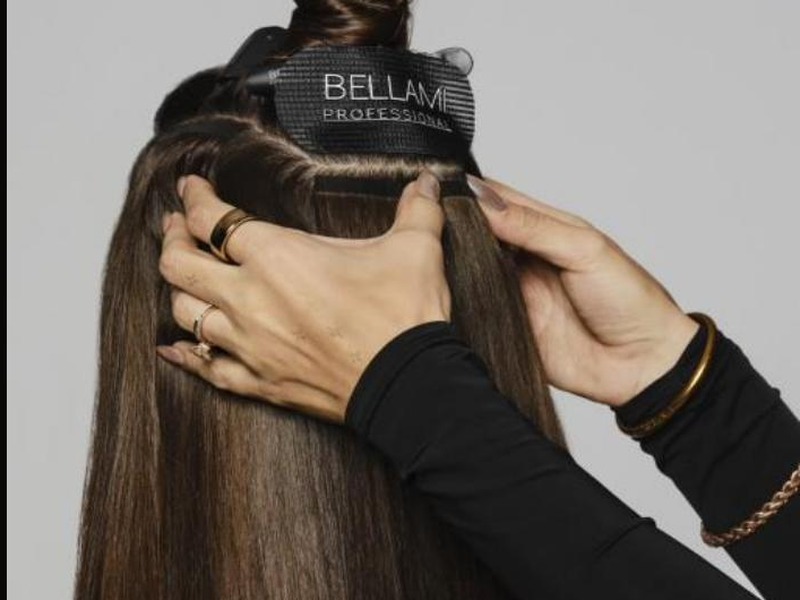 Stylist's hands installing a BELLAMI Professional weft close to the scalp