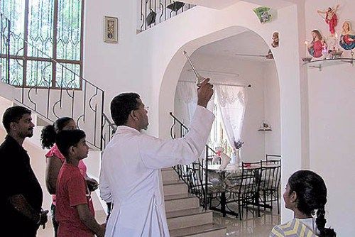 A priest blessing a home with holy water