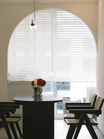 Elegant dining area with a table and chairs, complemented by Light Filtering Shangri-La Sheer Shades For Windows.