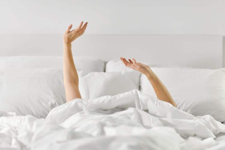 Someone lying in bed stretching