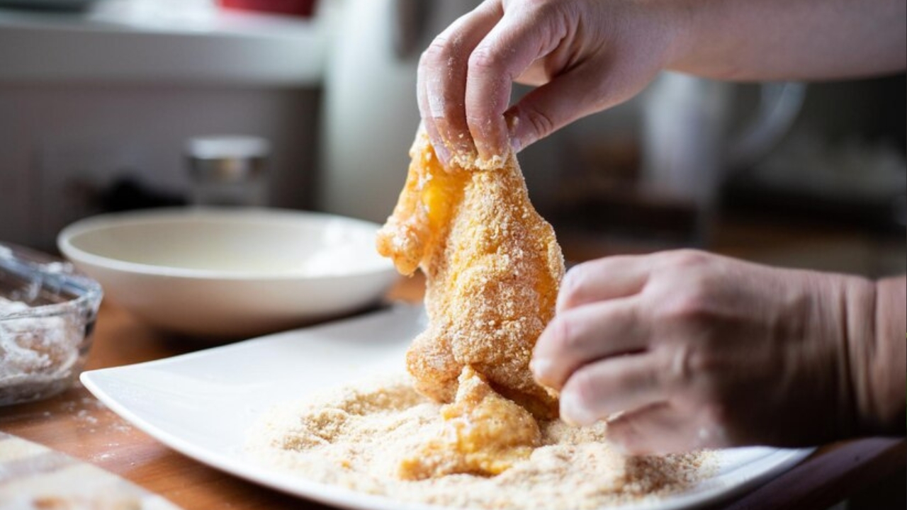 coating the chicken with bread crumbs