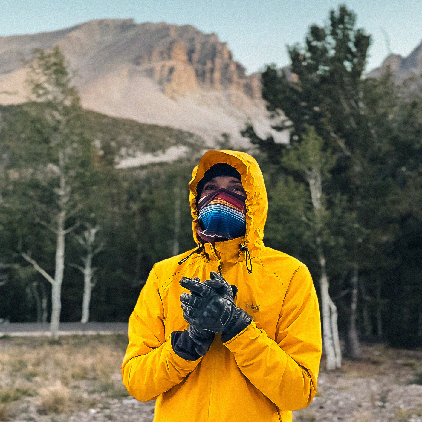 Motorcycle rider bundled in a yellow rain jacket, beanie, face covering, and black gloves at Wheeler Peak Campground in Great Basin National Park.