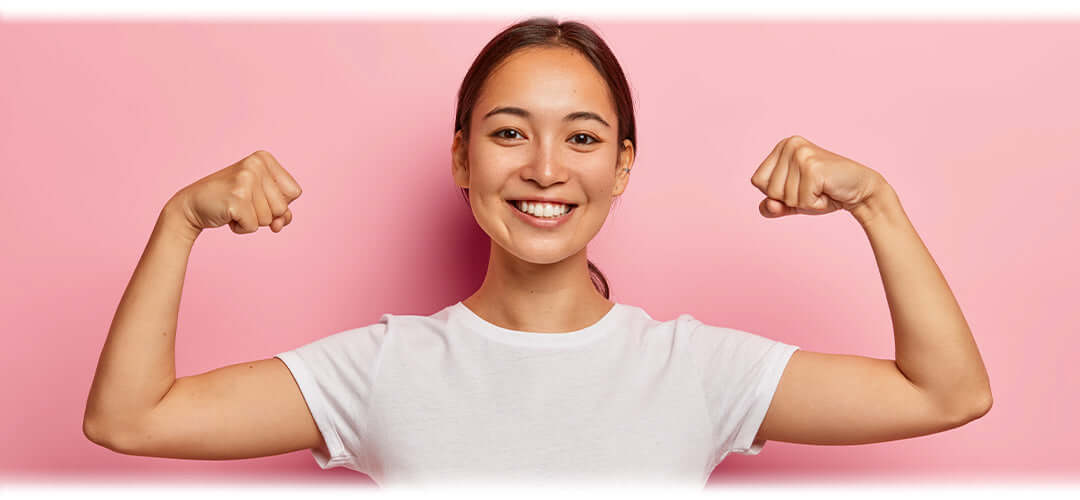 A confident woman flexing her arm muscles, symbolising a strong immune system and overall health.