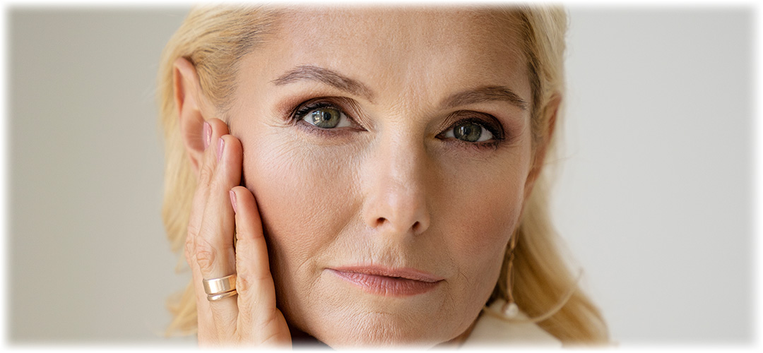 Close-up of a blonde woman touching her face, showcasing healthy and radiant skin. Lily & Loaf highlights the benefits of skincare and self-care.