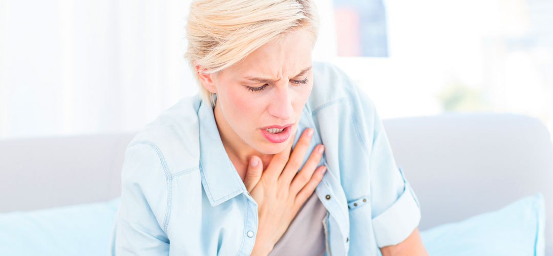 female on couch holding chest. struggling to breath