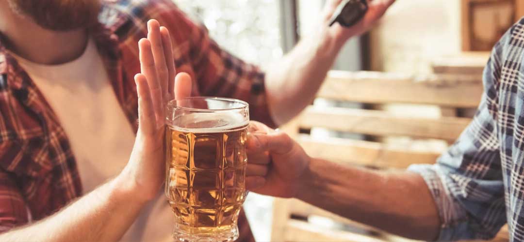 male saying no to a pint in bar