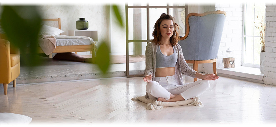 A woman meditating calmly in her bedroom