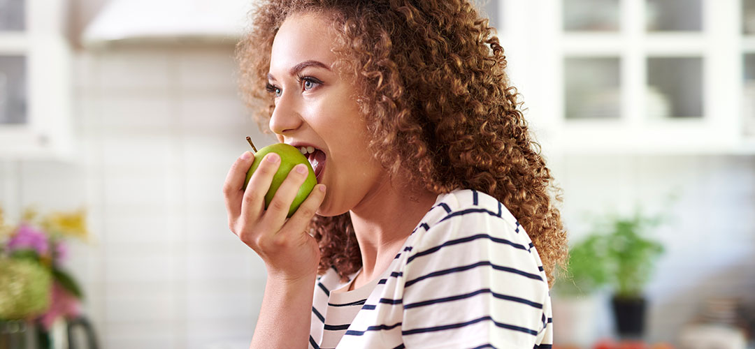lady taking bite out of a green apple