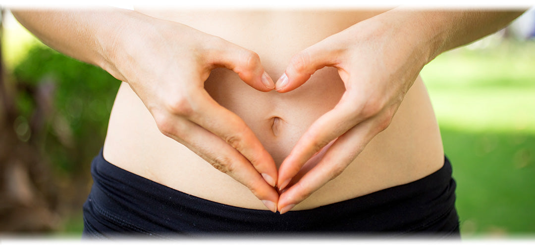 A woman holding her hand in a heart shape over her stomach