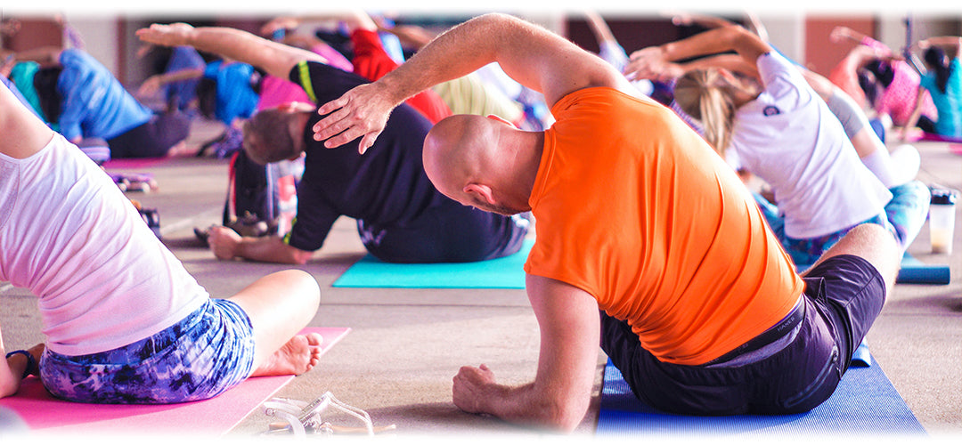 People participating in an exercise class, stretching on yoga mats
