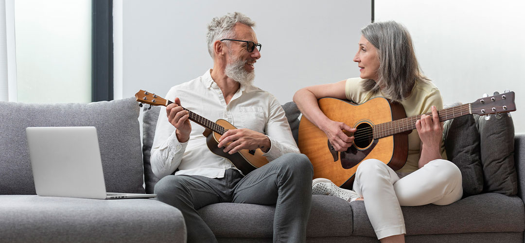 senior-couple-home-studying-guitar-ukulele-lessons-laptop