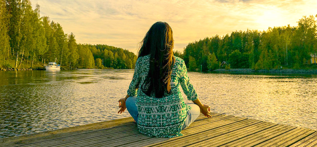 A woman looking out from the banks of a serene lake