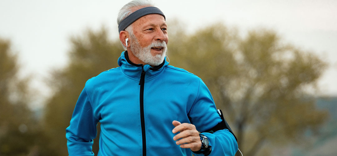 happy-senior-athlete-running-morning-nature-listening-music-earphones
