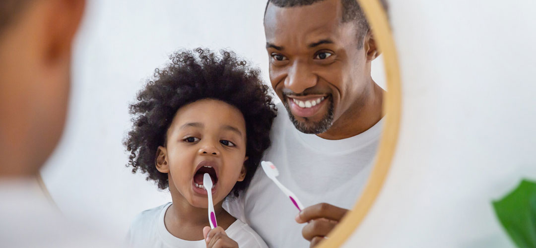 father son cleaning teeth