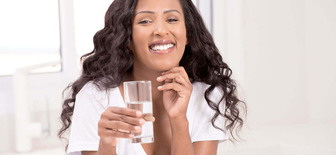 lady drinking a glass of water in the kitchen