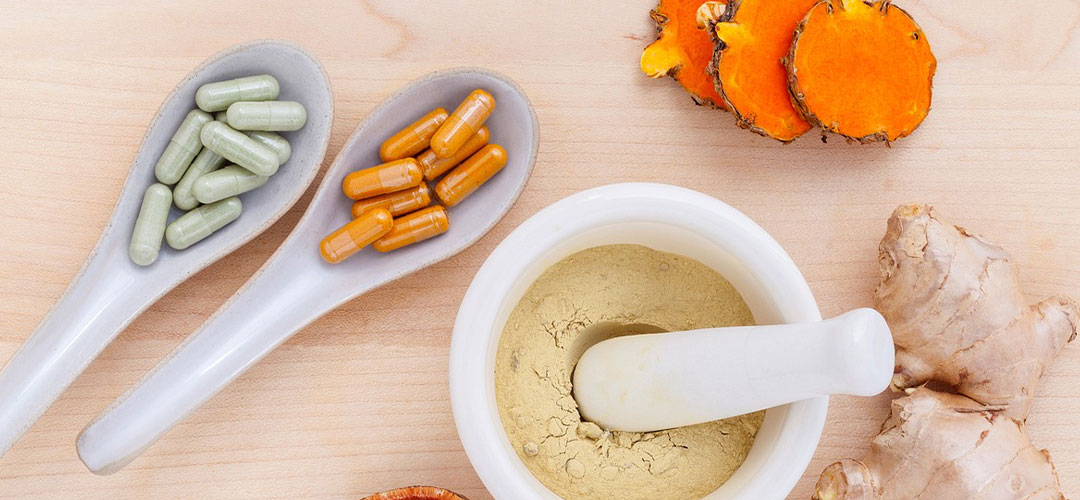 selection of supplements on spoons with fresh ginger next to them