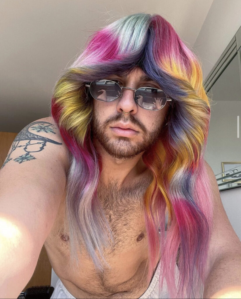man with sunglassses on and multi coloured long hair
