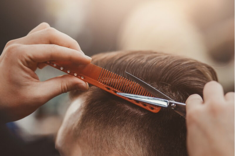 Barber scissors cutting hair over comb