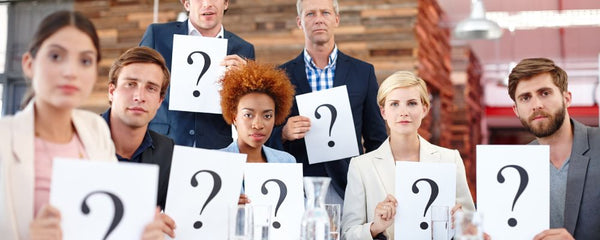 group of people holding up question mark signs implying they have questions