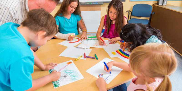 the smelly panda soap company children drawing at a table with a male teacher assisting